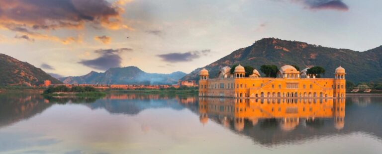 Jal Mahal in Jaipur, Rajasthan, reflected in Man Sagar Lake during sunset with Aravalli hills in the background.